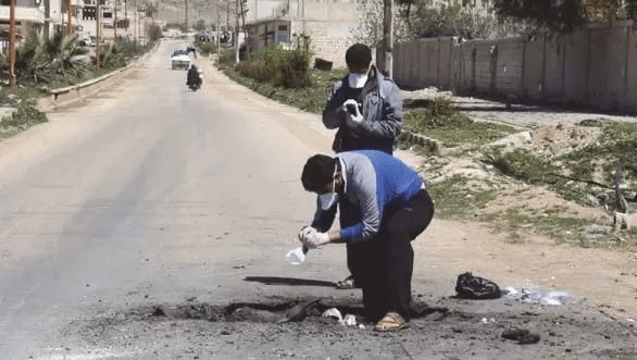 A person kneeling on the side of a road
Description automatically generated