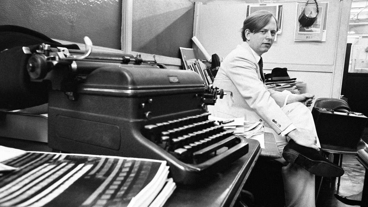 A person sitting at a desk using a typewriter

Description automatically generated
