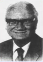 A person wearing glasses and a suit

Description automatically generated