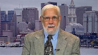 A person with a beard and mustache wearing a suit and tie

Description automatically generated