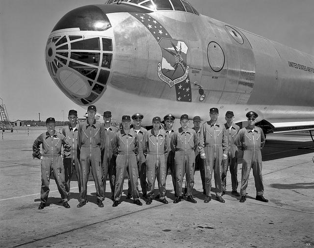 A group of men in uniform standing in front of a plane
Description automatically generated