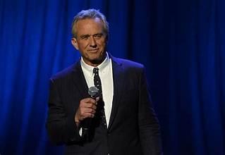 A person in a suit holding a microphone

Description automatically generated