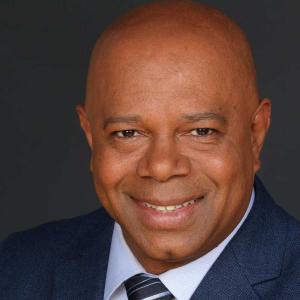 A person in a suit smiling
Description automatically generated