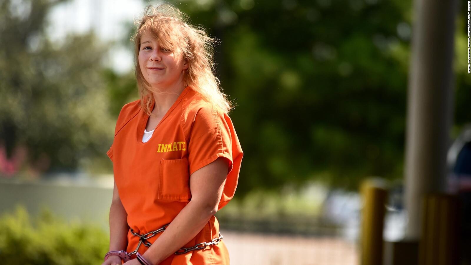 A person in orange prison uniform

Description automatically generated