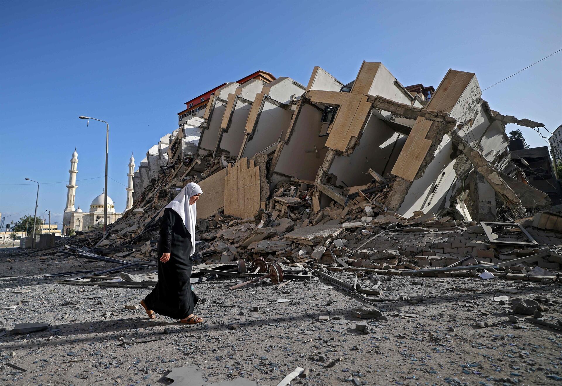 A person walking in front of a destroyed building
Description automatically generated