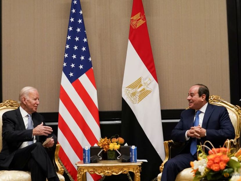 Two men sitting in chairs with flags

Description automatically generated