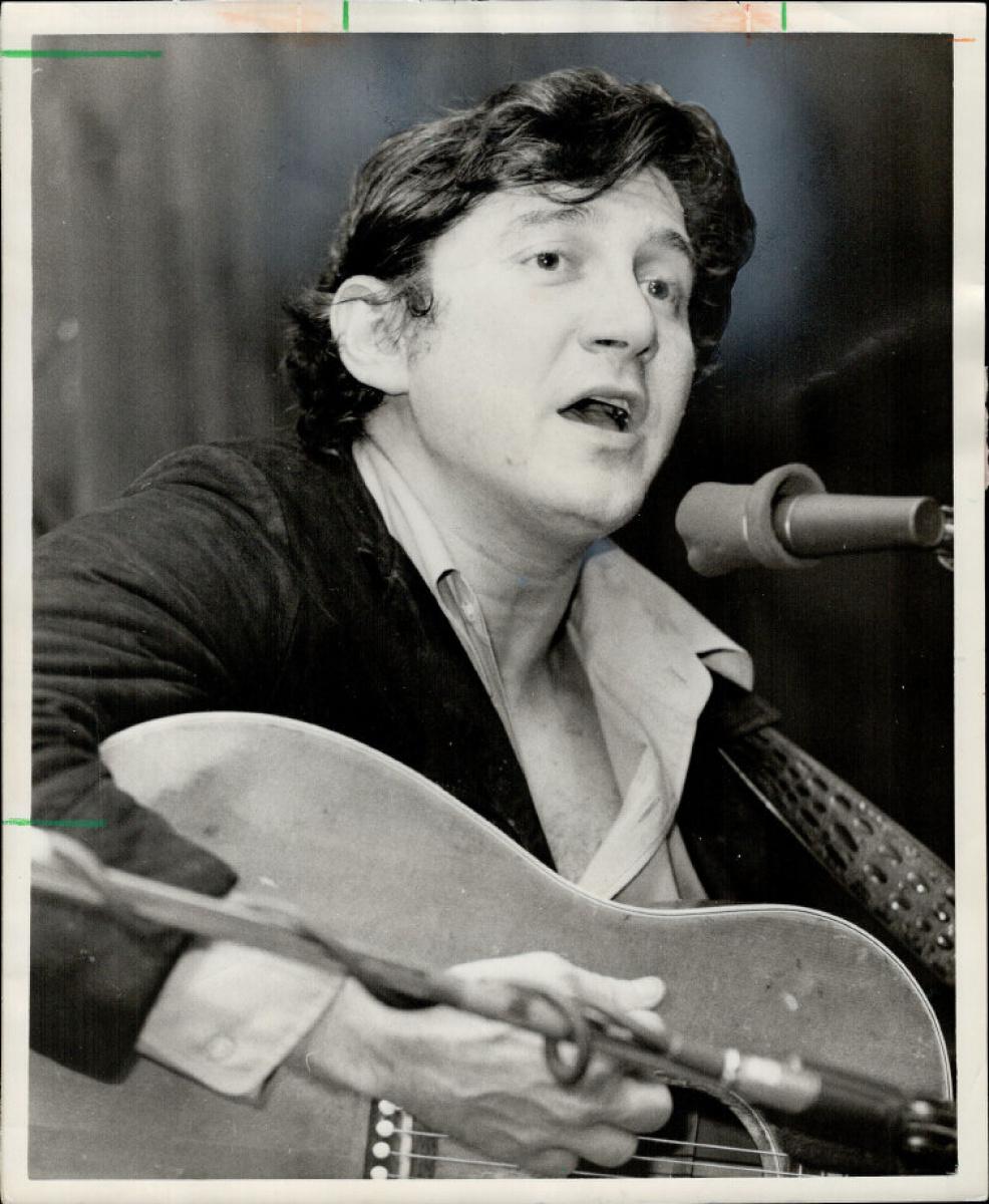 A person holding a guitar and singing into a microphone

Description automatically generated with low confidence