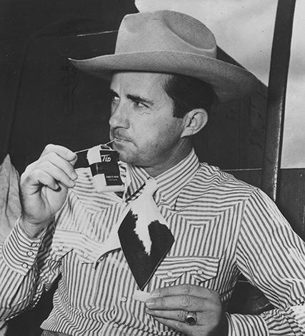 A person in a cowboy hat smoking a cigarette

Description automatically generated
