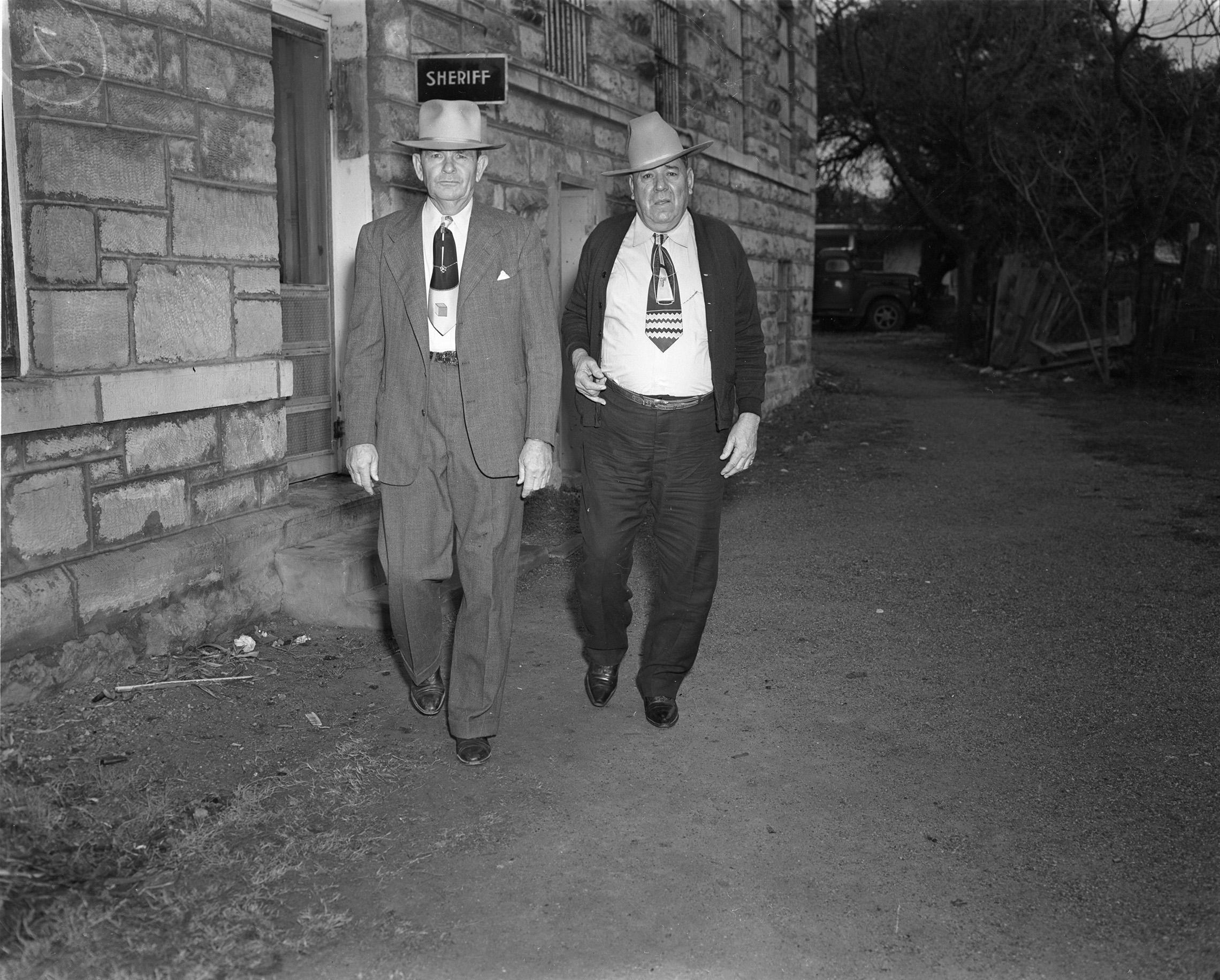 A person in a hat walking with another person in a hat

Description automatically generated