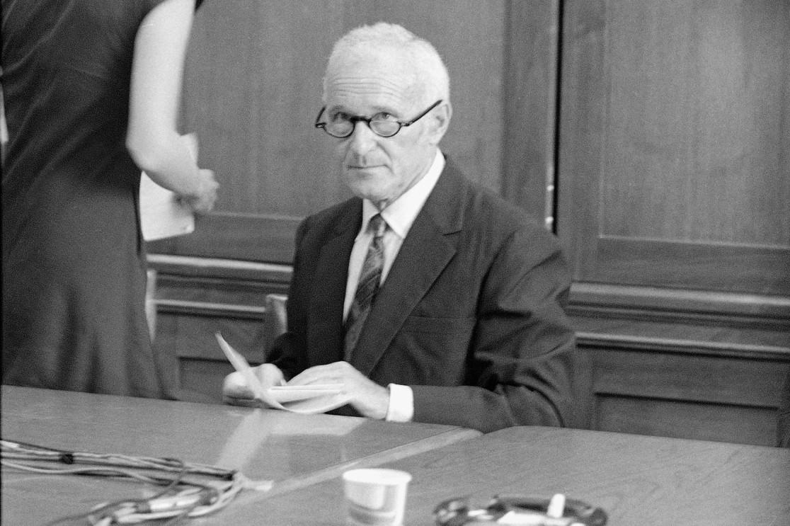 A person in a suit and tie sitting at a table

Description automatically generated with low confidence