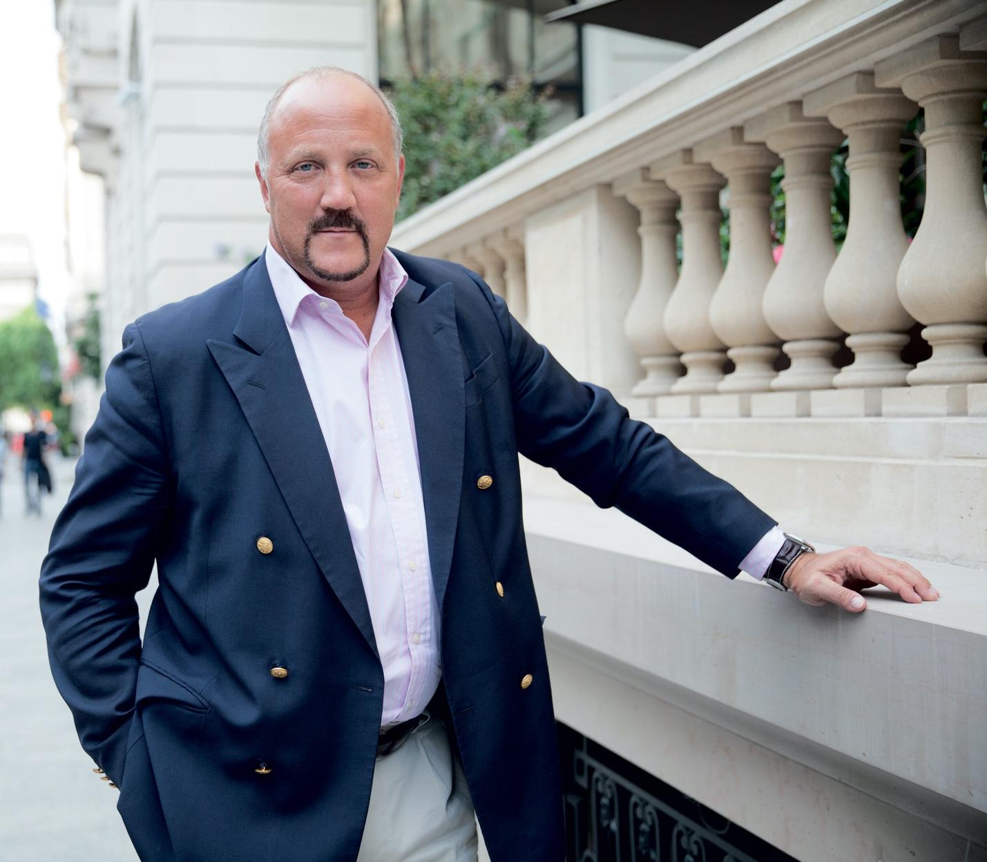 A person in a suit leaning on a railing
Description automatically generated with low confidence