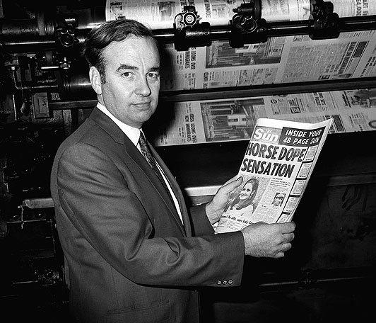 A person in a suit reading a newspaper
Description automatically generated