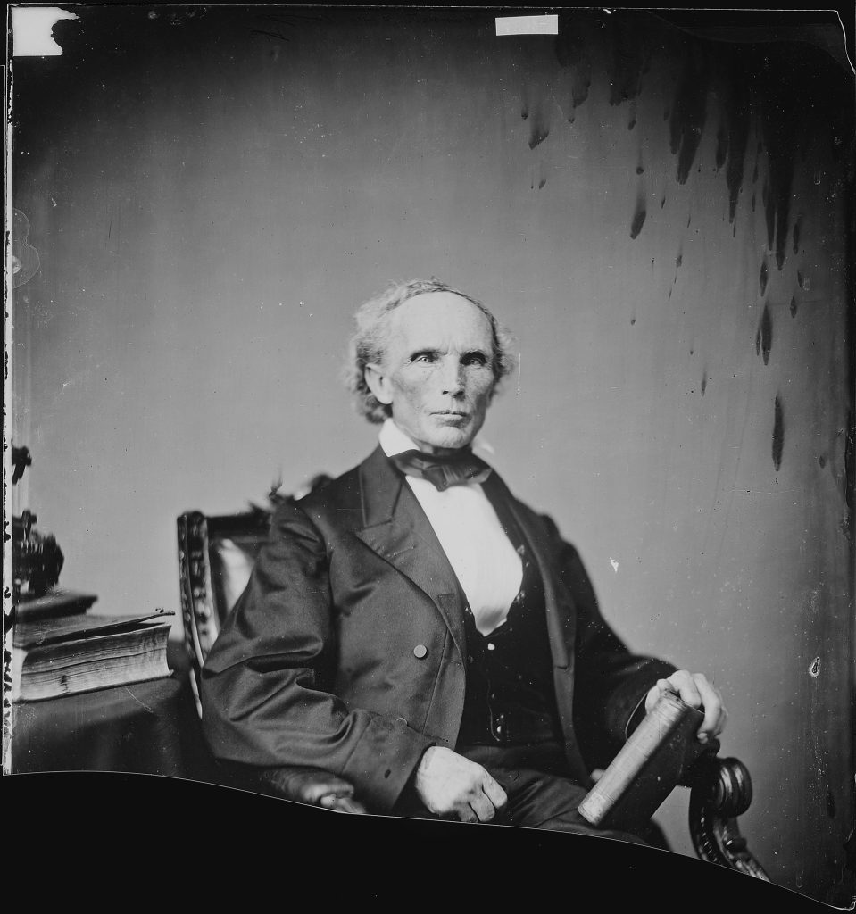 A person in a suit sitting in a chair
Description automatically generated with medium confidence