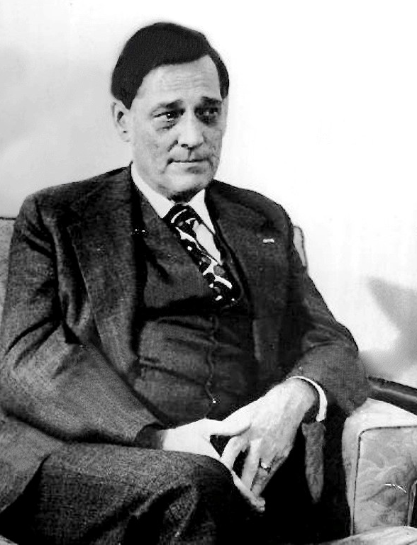 A person in a suit sitting in a chair

Description automatically generated