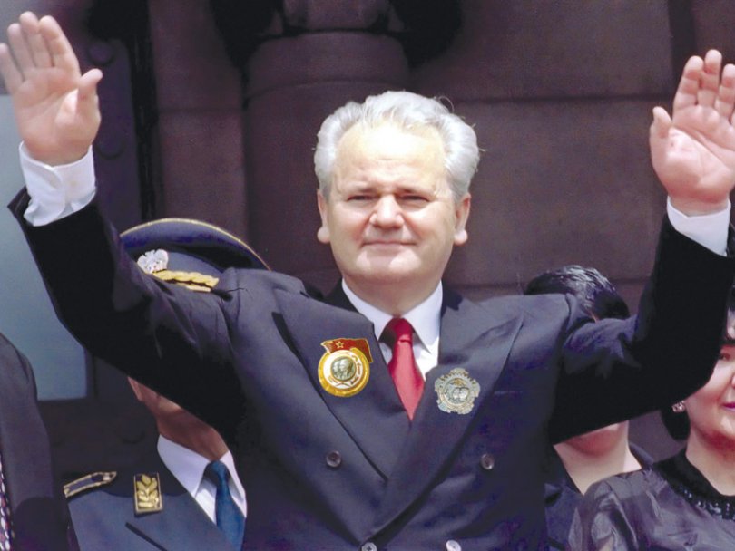 A person in a suit with his arms raised
Description automatically generated