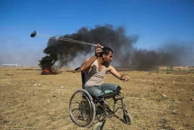 A person in a wheelchair with a selfie stick
Description automatically generated