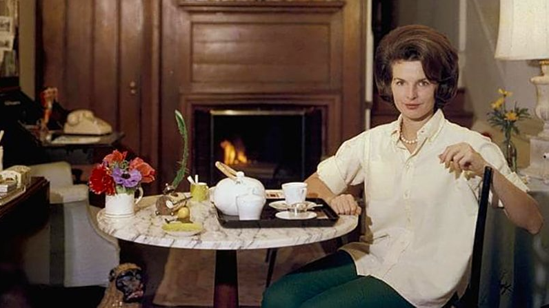 A person sitting at a table with tea cups and teapots

Description automatically generated