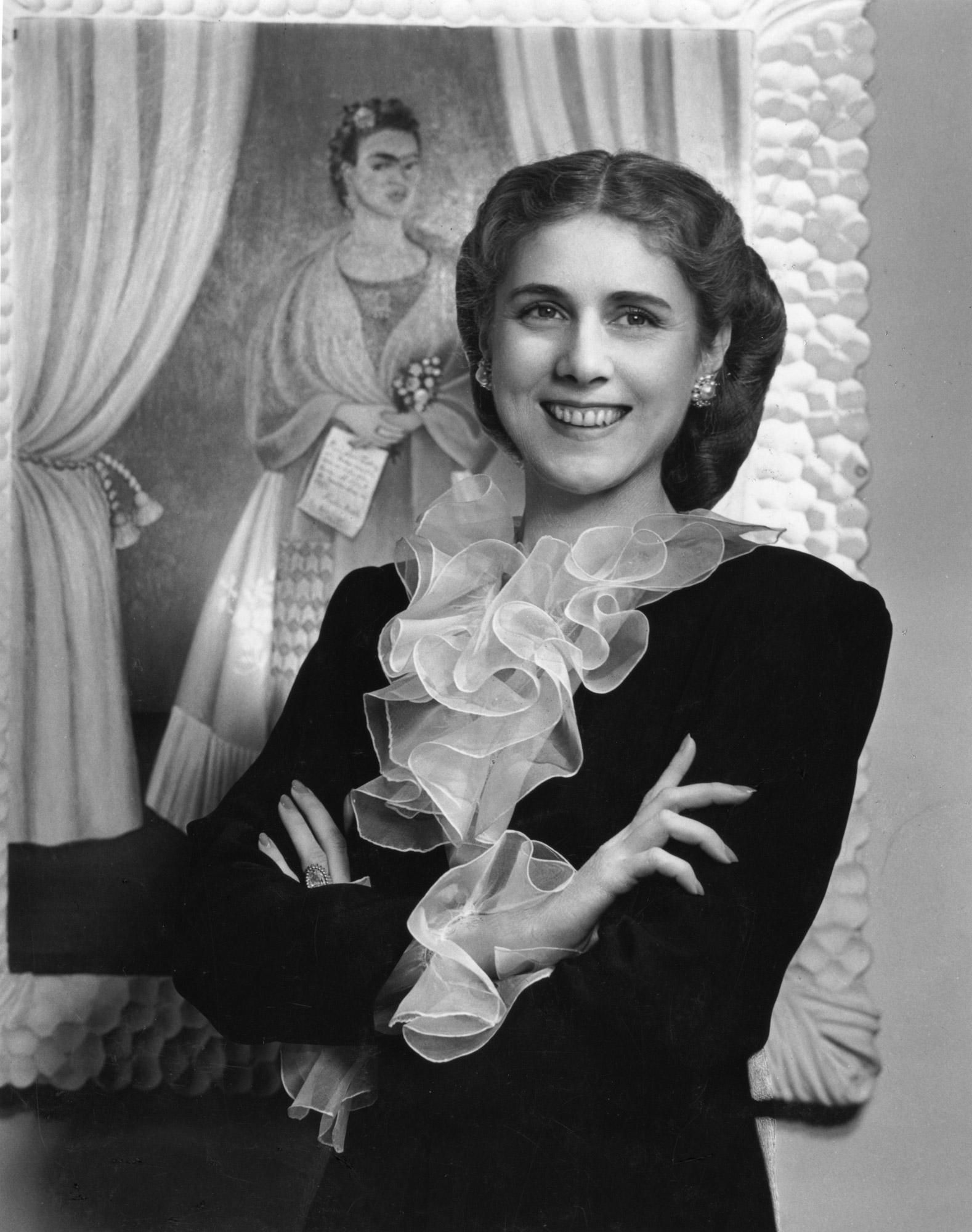 A person smiling in front of a painting

Description automatically generated