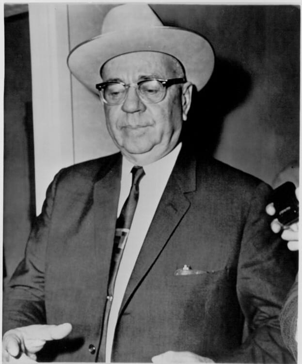 A person wearing a hat and suit Description automatically generated