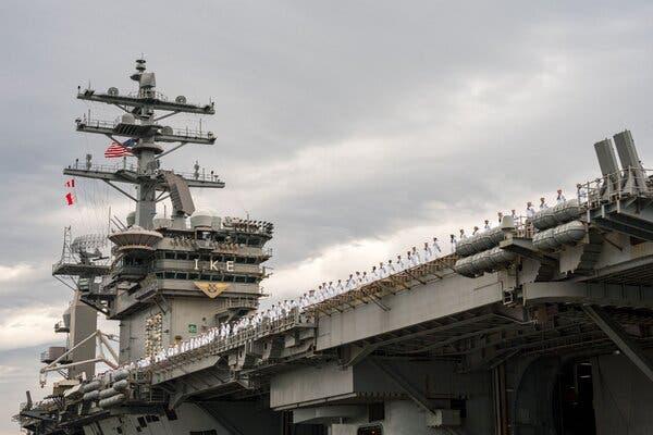 Sailors standing on an aircraft carrier.