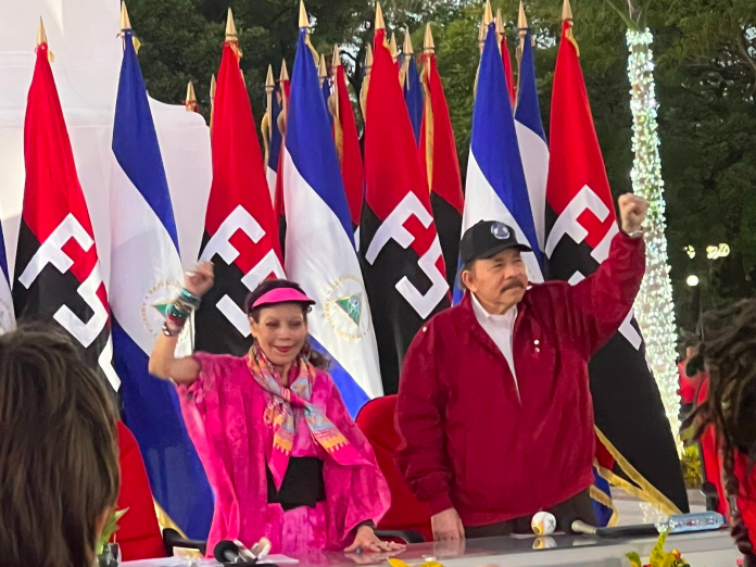 A group of people standing in front of flags

Description automatically generated