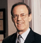 A person wearing glasses and a suit

Description automatically generated