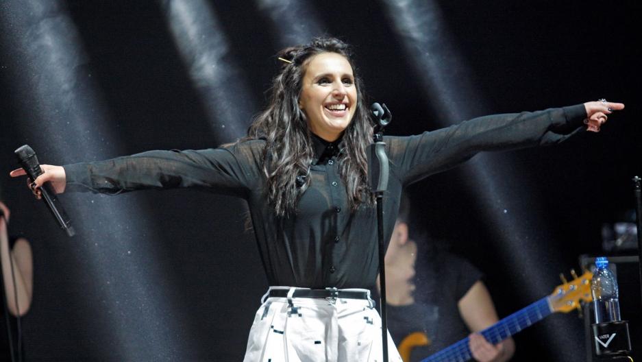 A person with her arms out and a microphone

Description automatically generated