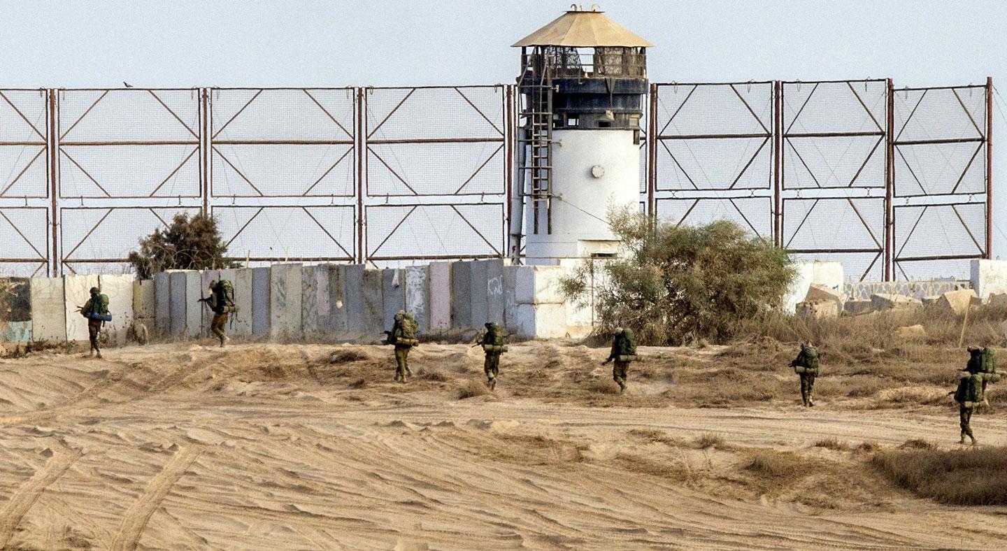 Israeli soldiers walk past a fence along Israel's border with the Gaza Strip, on August 4, 2014. An eight-year-old girl was killed and 30 people wounded in a strike on the beachfront Shati refugee camp in Gaza City just minutes into an Israeli-declared truce, medics said. AFP PHOTO / JACK GUEZ (Photo credit should read JACK GUEZ/AFP/Getty Images)