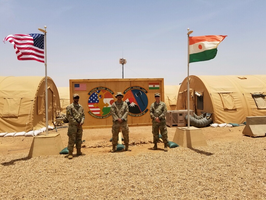 A group of men standing in front of tents
Description automatically generated