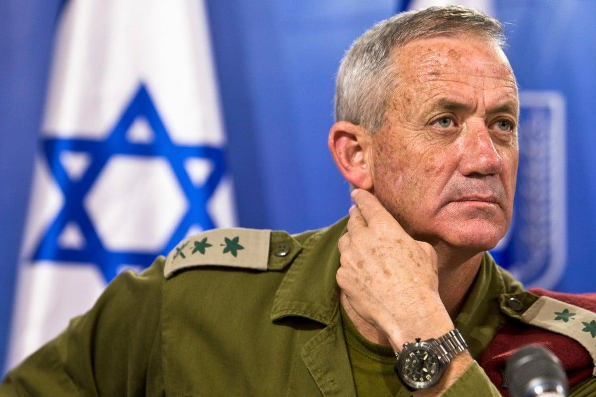 A person in military uniform with a hand on his neck

Description automatically generated