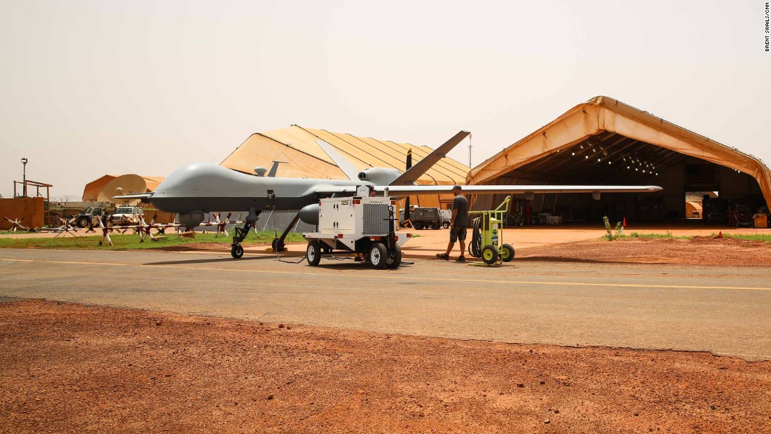 A person standing next to a military aircraft
Description automatically generated