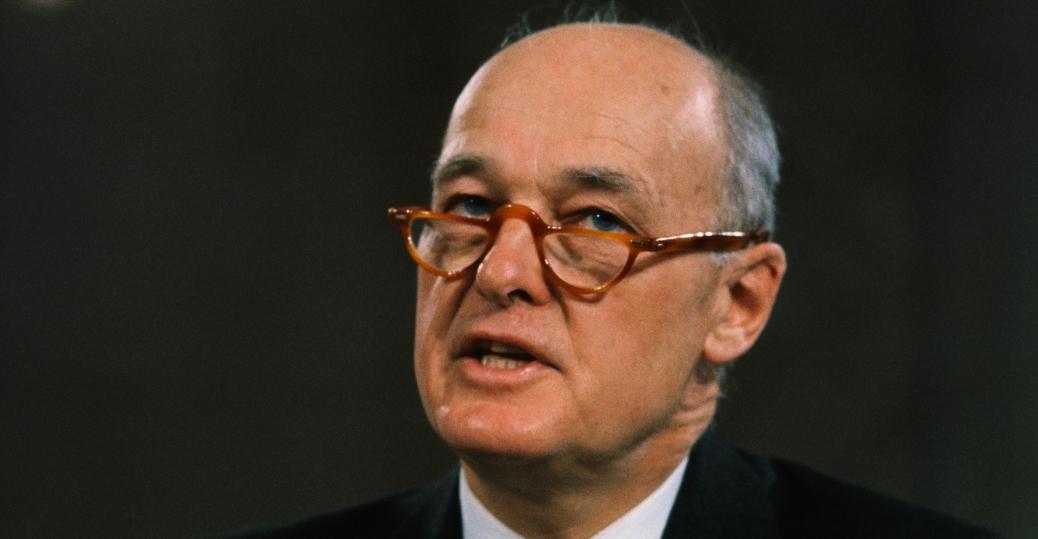 A person wearing glasses and a suit

Description automatically generated