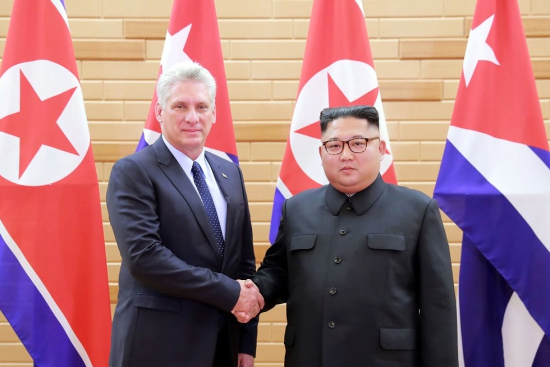 Two men shaking hands in front of flags

Description automatically generated