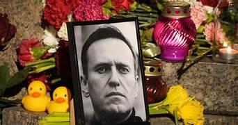 A black and white photo of a person in a frame next to flowers

Description automatically generated