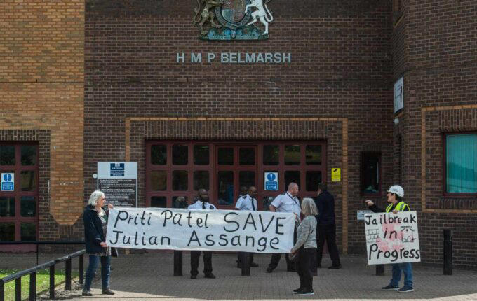 A group of people holding signs outside of a building

Description automatically generated