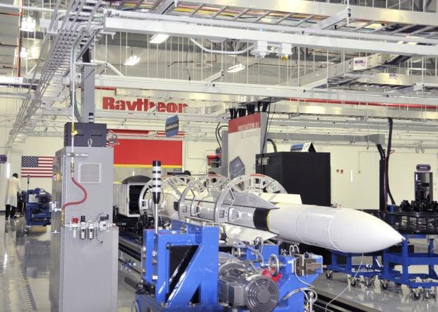 A large white rocket in a factory

Description automatically generated