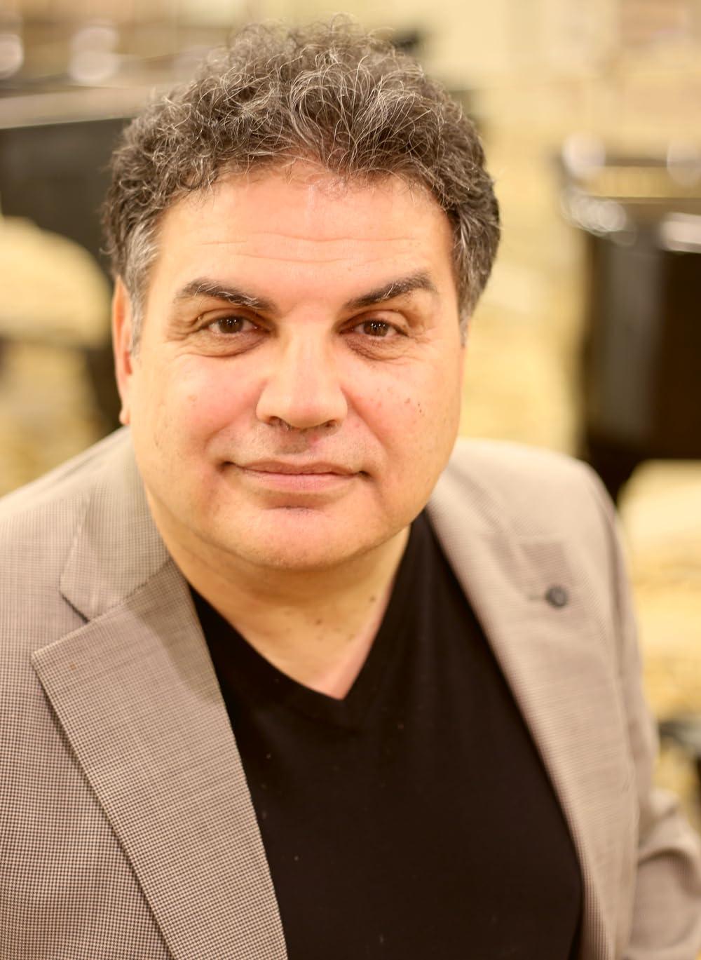 A person in a black shirt and tan jacket

Description automatically generated