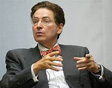 A person in a suit and glasses

Description automatically generated