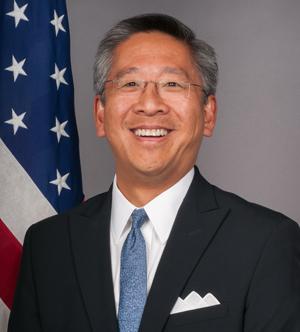 A person in a suit and tie smiling

Description automatically generated
