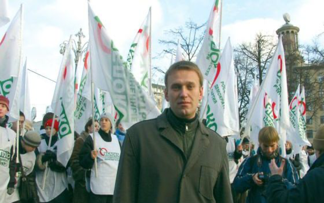 A person standing in front of a group of people holding flags Description automatically generated