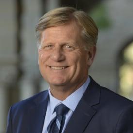 A person in a suit smiling

Description automatically generated