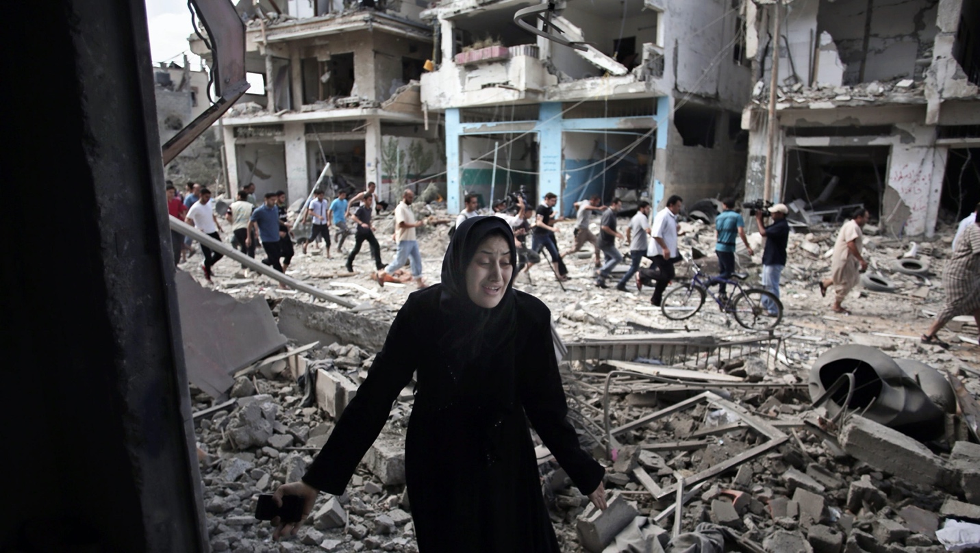 A person in black standing in rubble

Description automatically generated