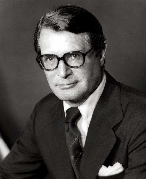 A person wearing glasses and a suit

Description automatically generated