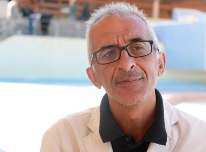 A person wearing glasses and a white coat

Description automatically generated