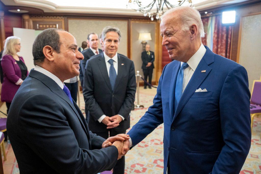 Two men shaking hands in a room

Description automatically generated