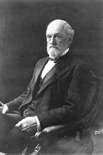 A person in a suit sitting in a chair
Description automatically generated