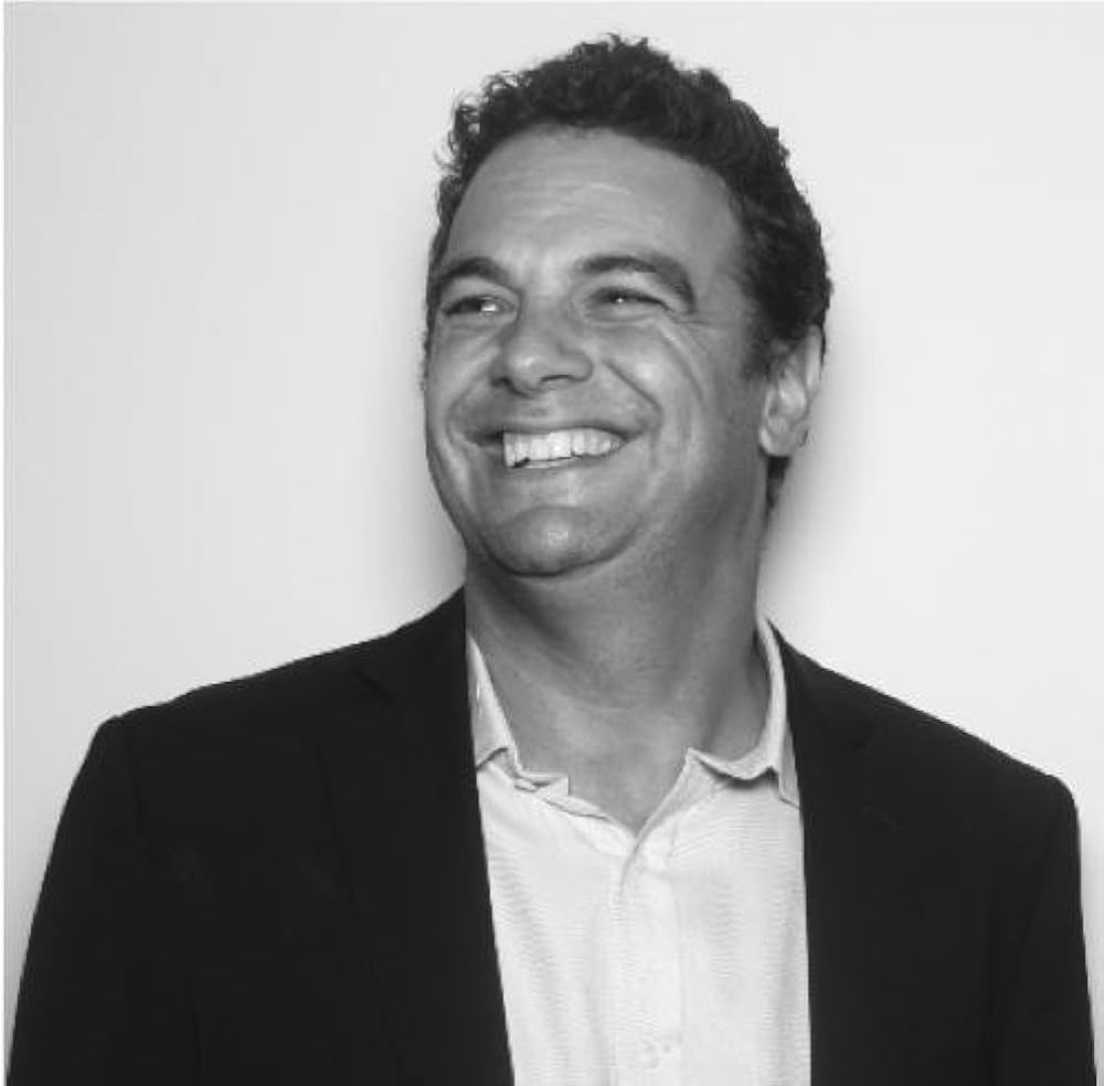 A person in a suit smiling

Description automatically generated