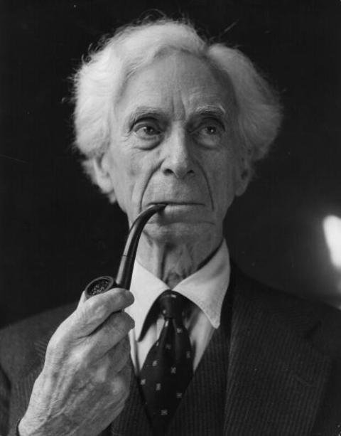 A person in a suit smoking a pipe

Description automatically generated
