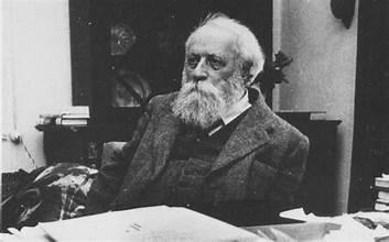 A person with a beard sitting at a desk

Description automatically generated