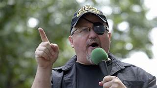 A person with an eye patch holding a microphone

Description automatically generated